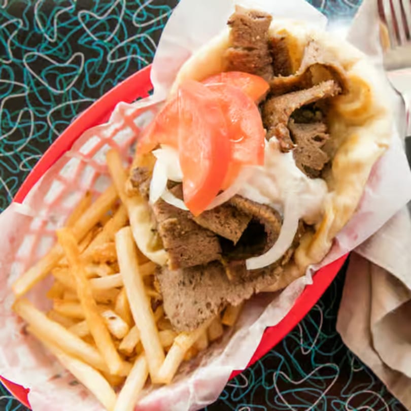 A Bo-Bo's Gyros pita sandwich with meat, tomatoes, onions, and sauce, served with fries.